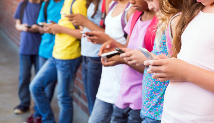 Cute pupils using mobile phone